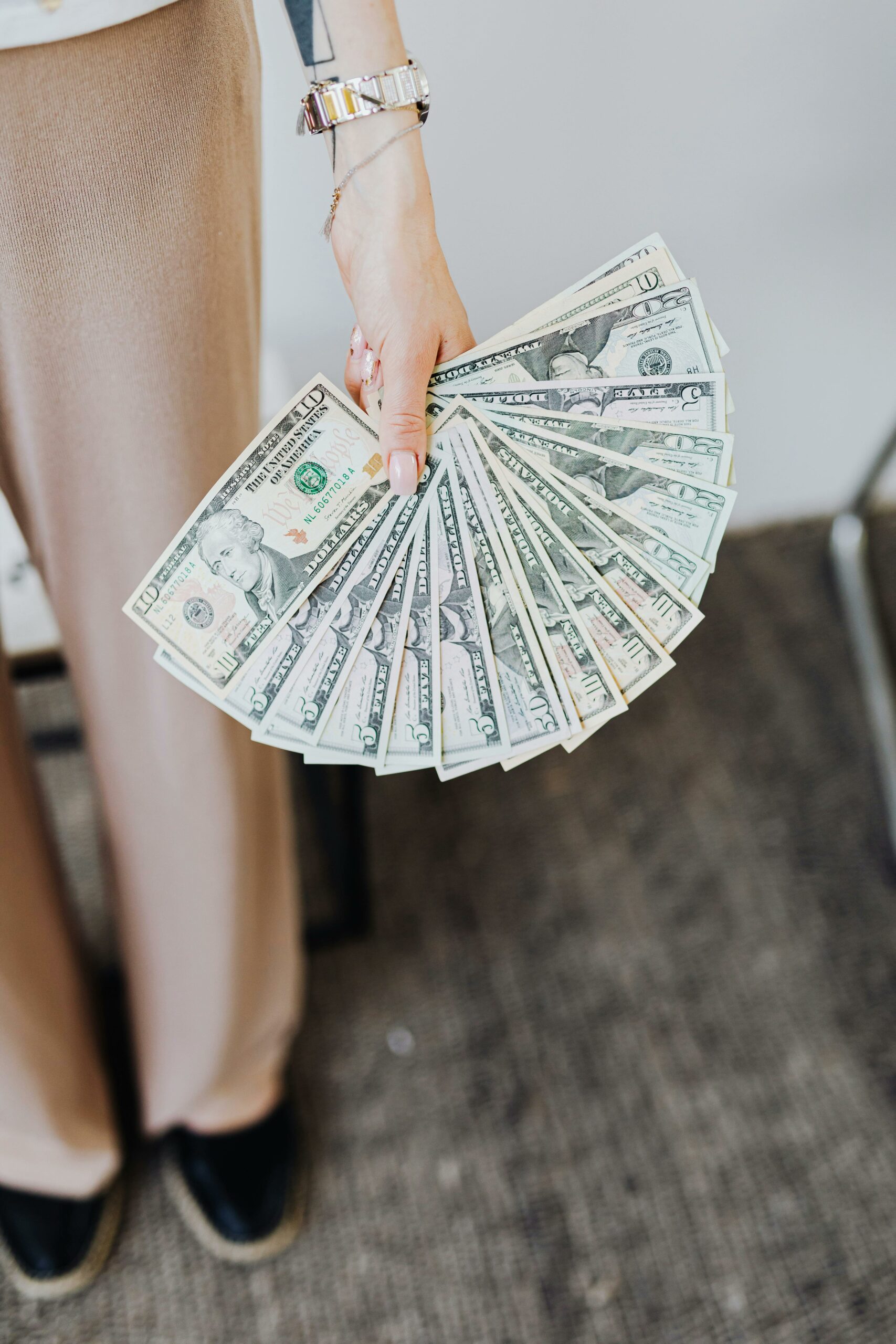 Hand holding fanned out US dollar bills.