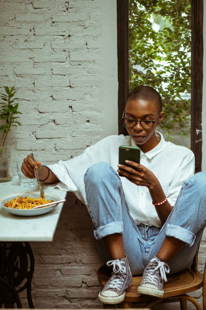 A woman using her phone while eating, symbolizing the need to balance technology use and mindful habits.