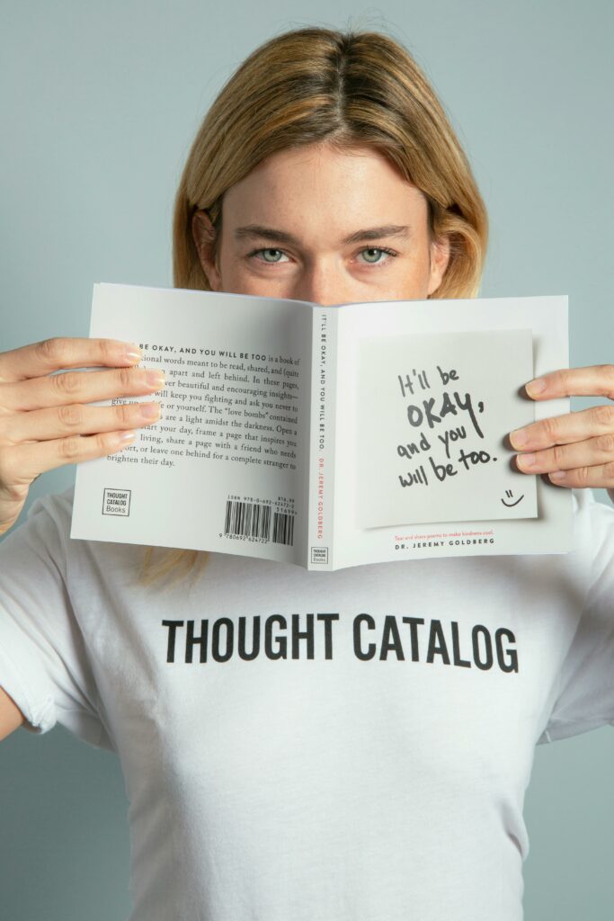 Woman holding a book with a positive message on a sticky note.