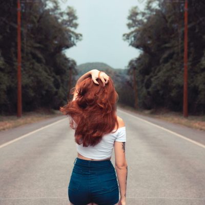 Red-haired woman walking down an empty road, symbolizing embracing the past and moving forward